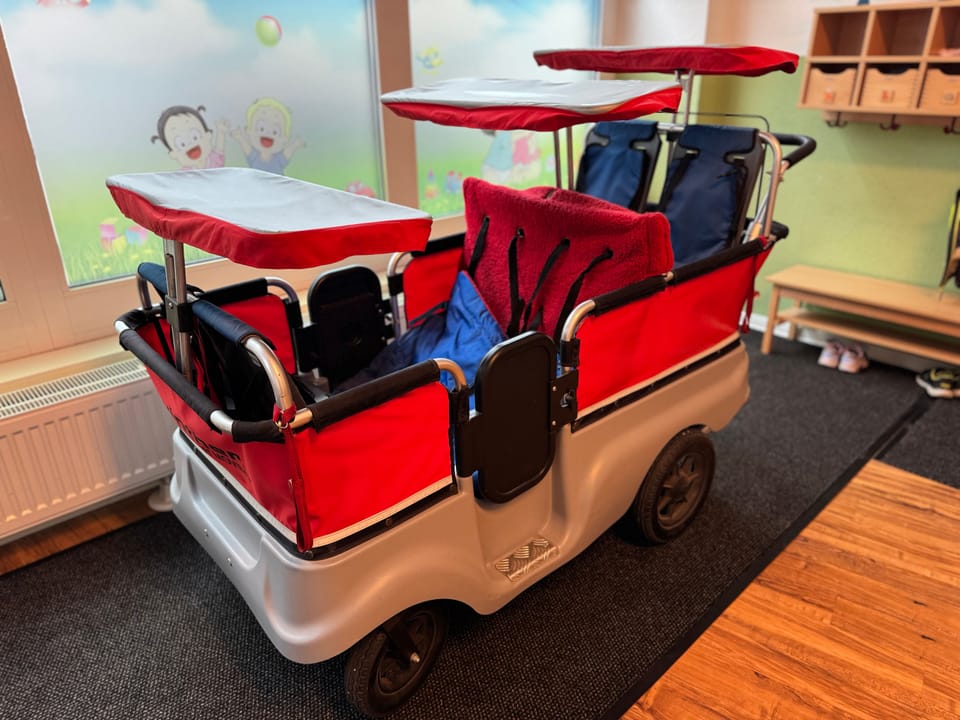 Roter Krippenwagen mit mehreren Sitzplätzen und Sonnendächern