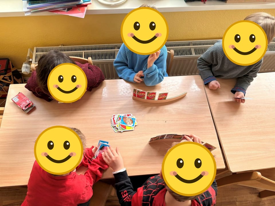 Vier Kinder spielen gemeinsam ein Kartenspiel am Tisch