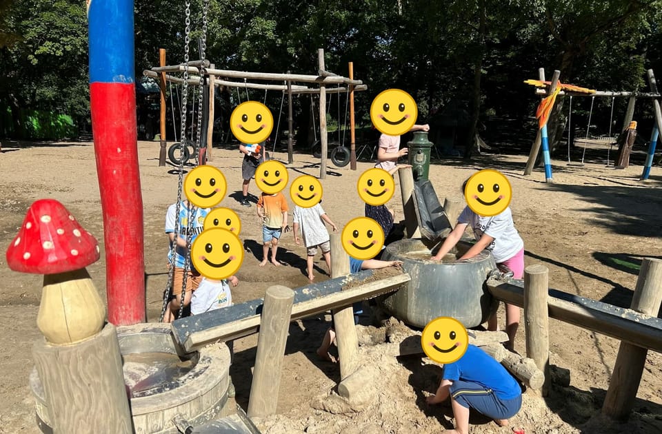 Kinder spielen auf einem Wasserspielplatz mit Sand, Wasserpumpe und einer großen Wanne